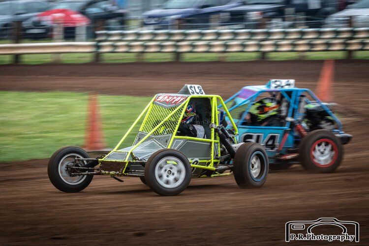 Two go karts are racing on a dirt track.