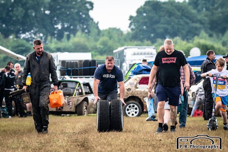 A group of men are carrying tires in a field.