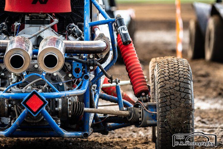 A woman is sitting on top of a muddy buggy in a field.