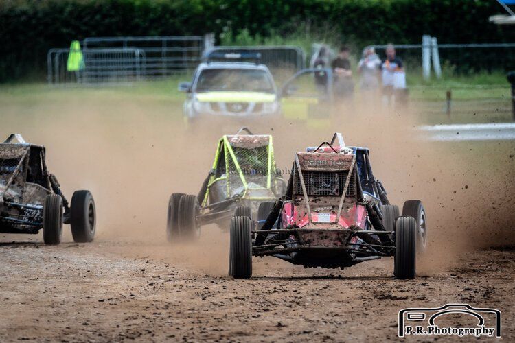 A group of buggies are racing on a dirt track.