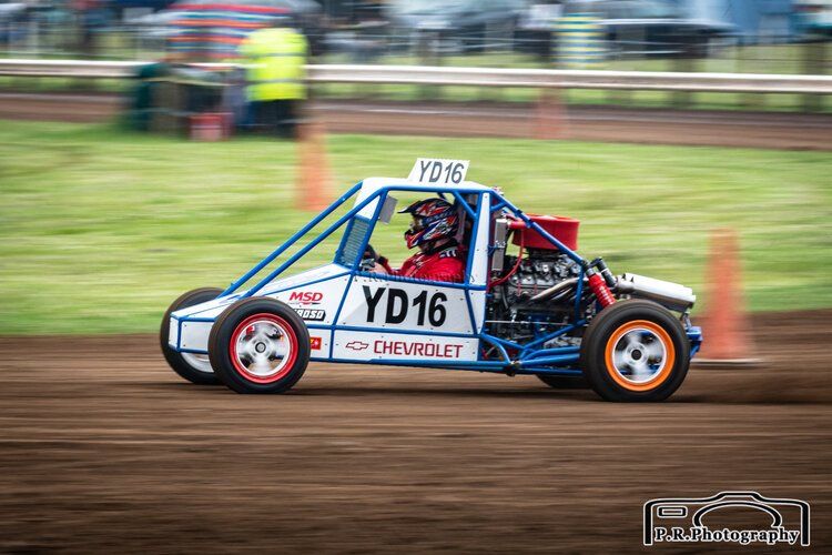 A man is driving a buggy on a dirt track.