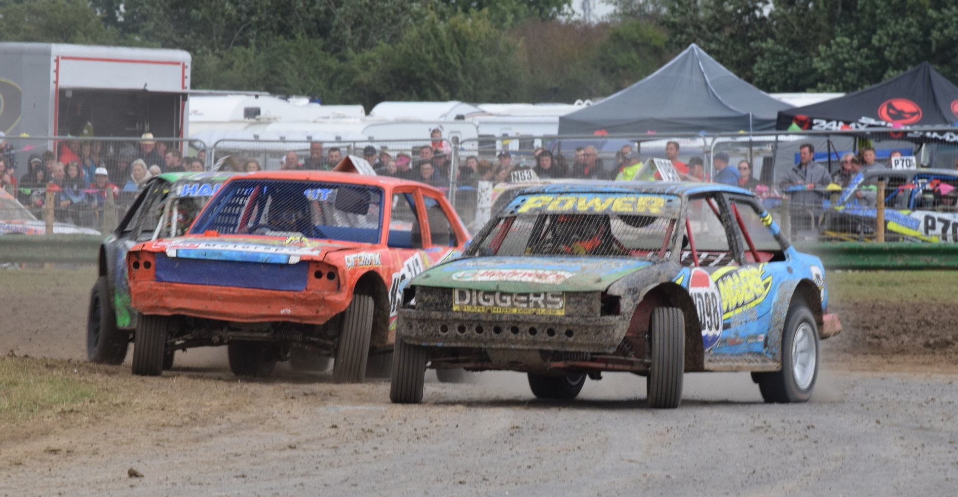 A group of cars are racing on a dirt track.
