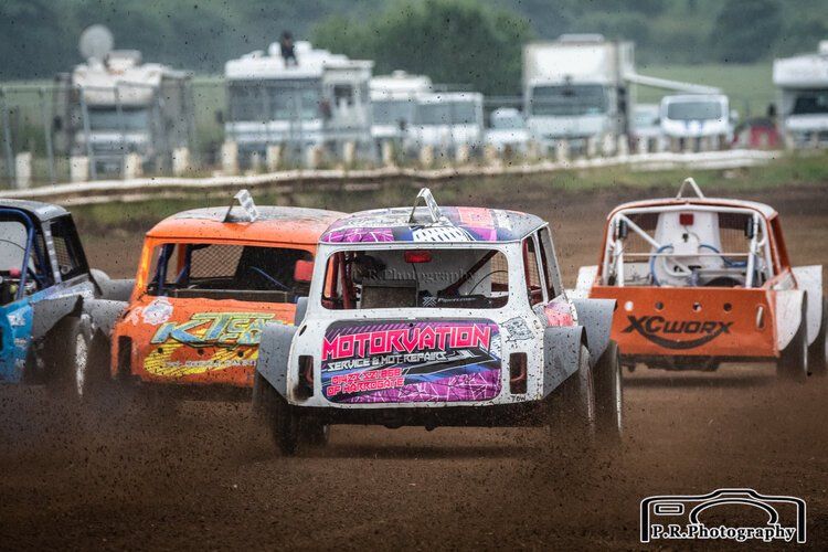 A group of cars are racing on a dirt track.