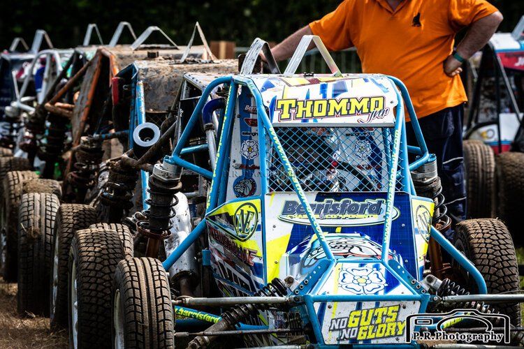 A man standing next to a buggy that says thommo on it