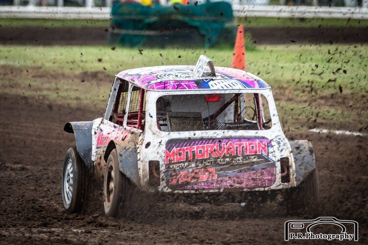 A race car is driving through the mud on a dirt track.