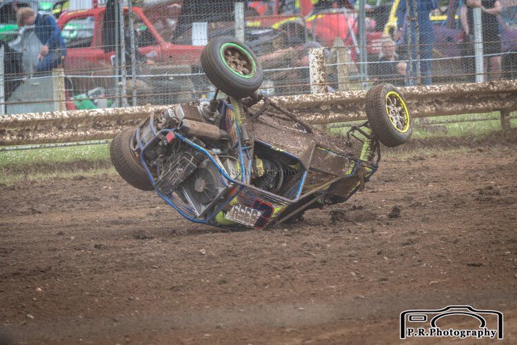 A race car is going down on its side on a dirt track.