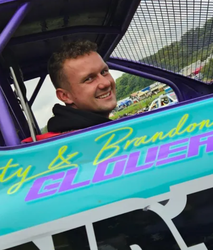A man is sitting in a race car with the name brandon on the side