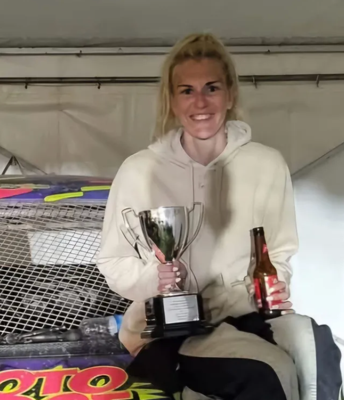 A woman is holding a trophy and a bottle of beer