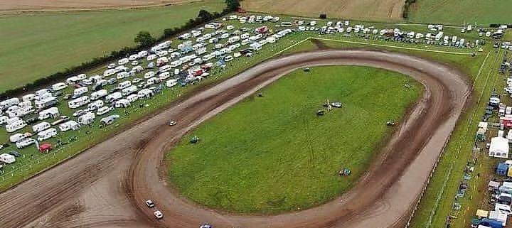 An aerial view of a dirt track with a lot of tents in the background.