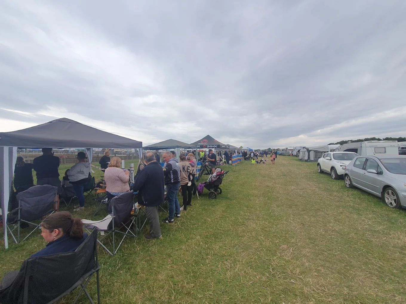 A group of people are standing under tents in a field.