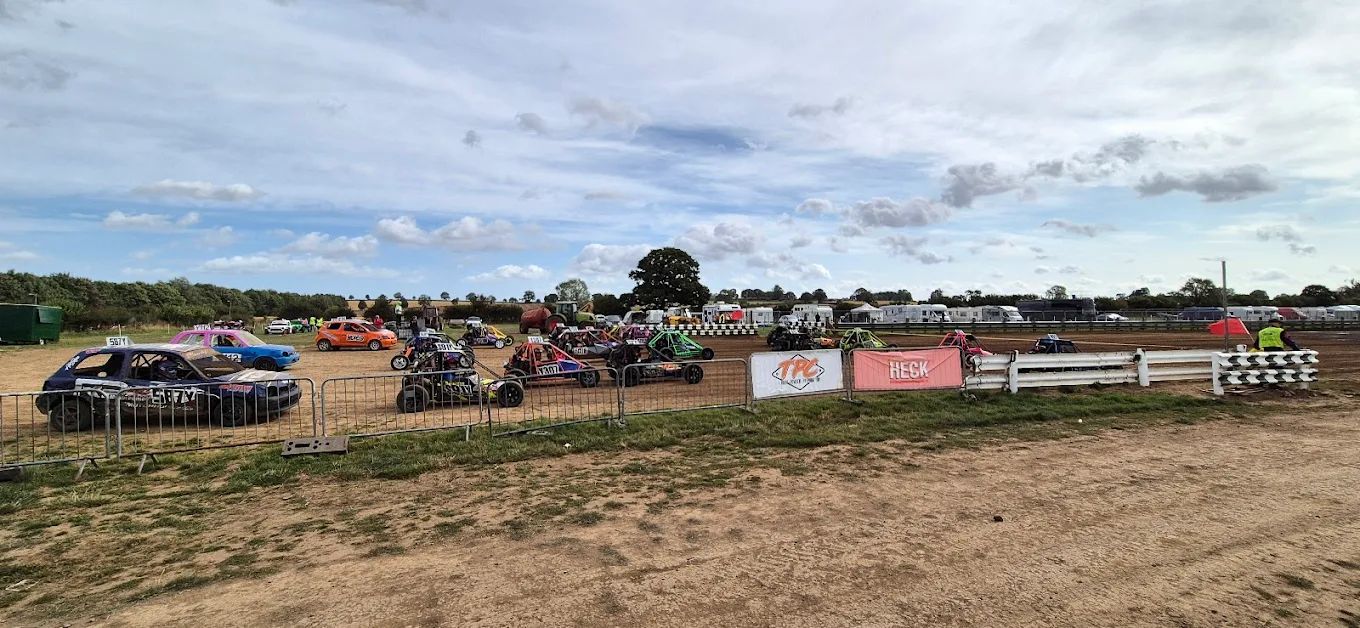 A group of cars are parked in a dirt field.