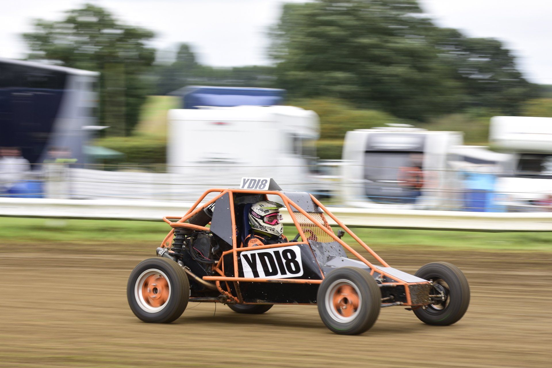 A person is driving a buggy on a dirt track.