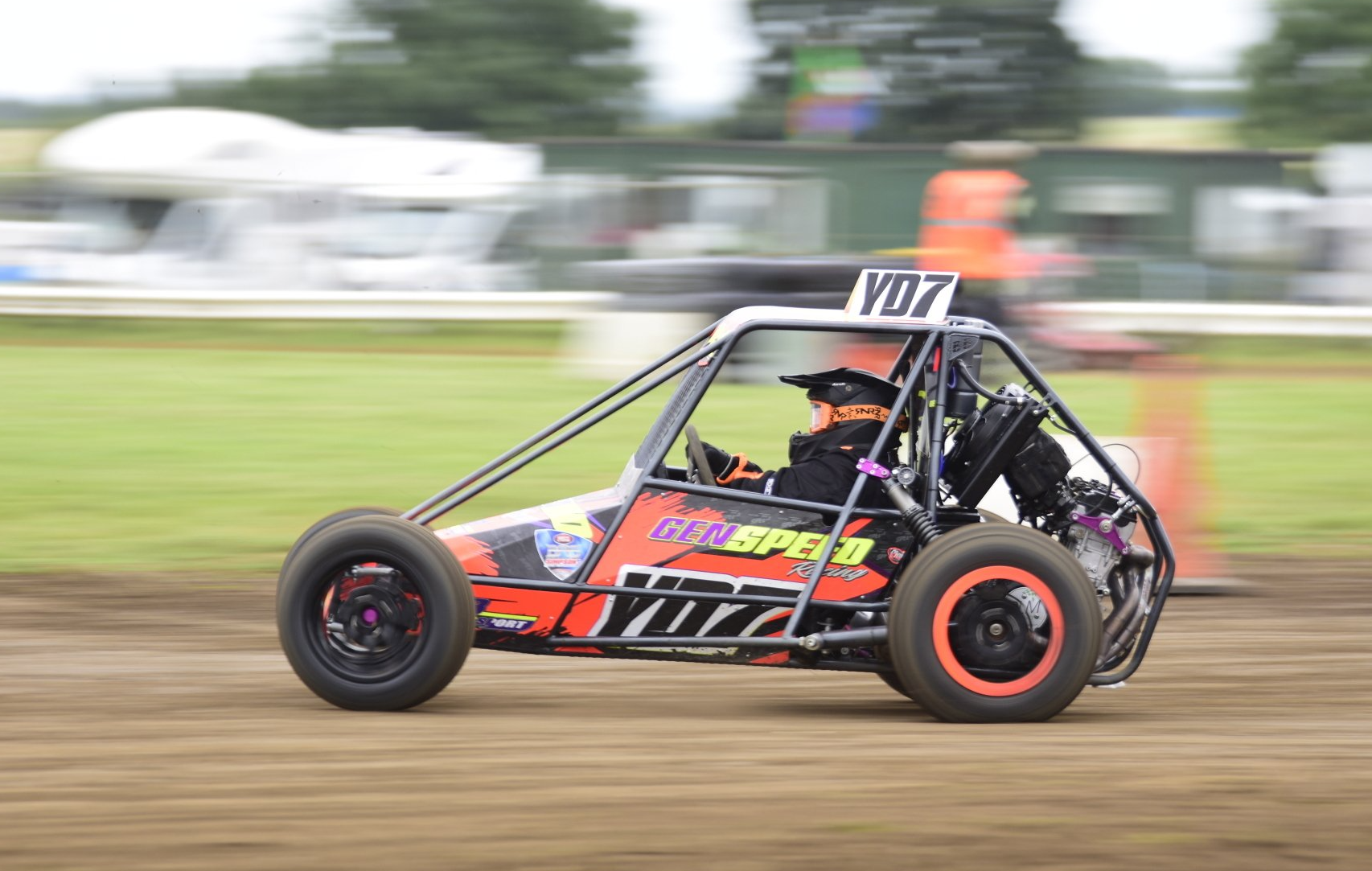 A person is driving a buggy on a dirt track.