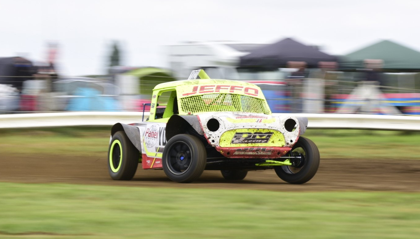 A race car is driving down a dirt track.