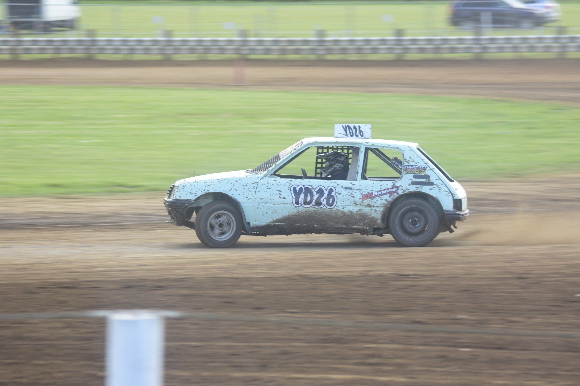 A white race car is driving on a dirt track.