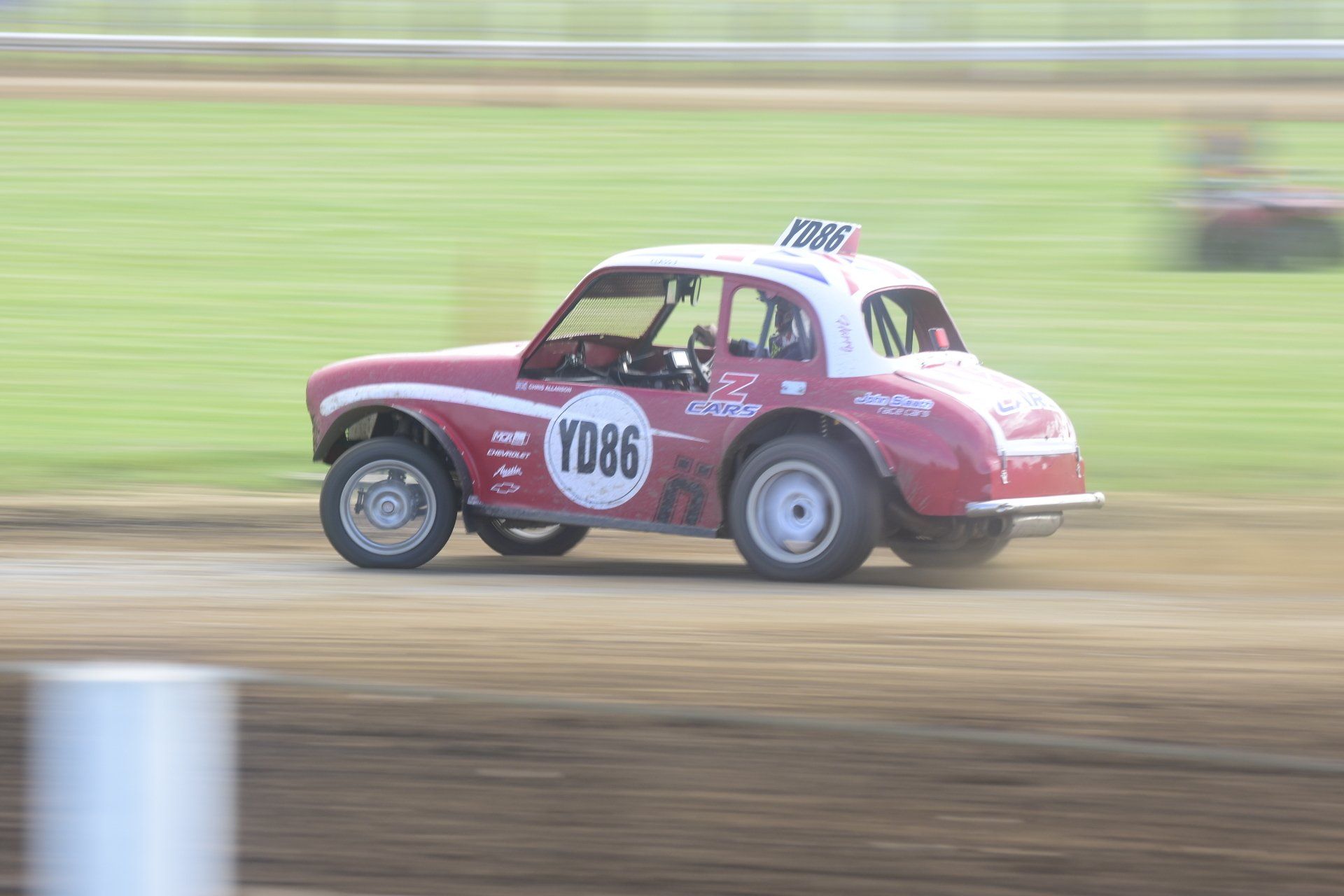 A red race car with the number rd86 on the side is driving on a dirt track.
