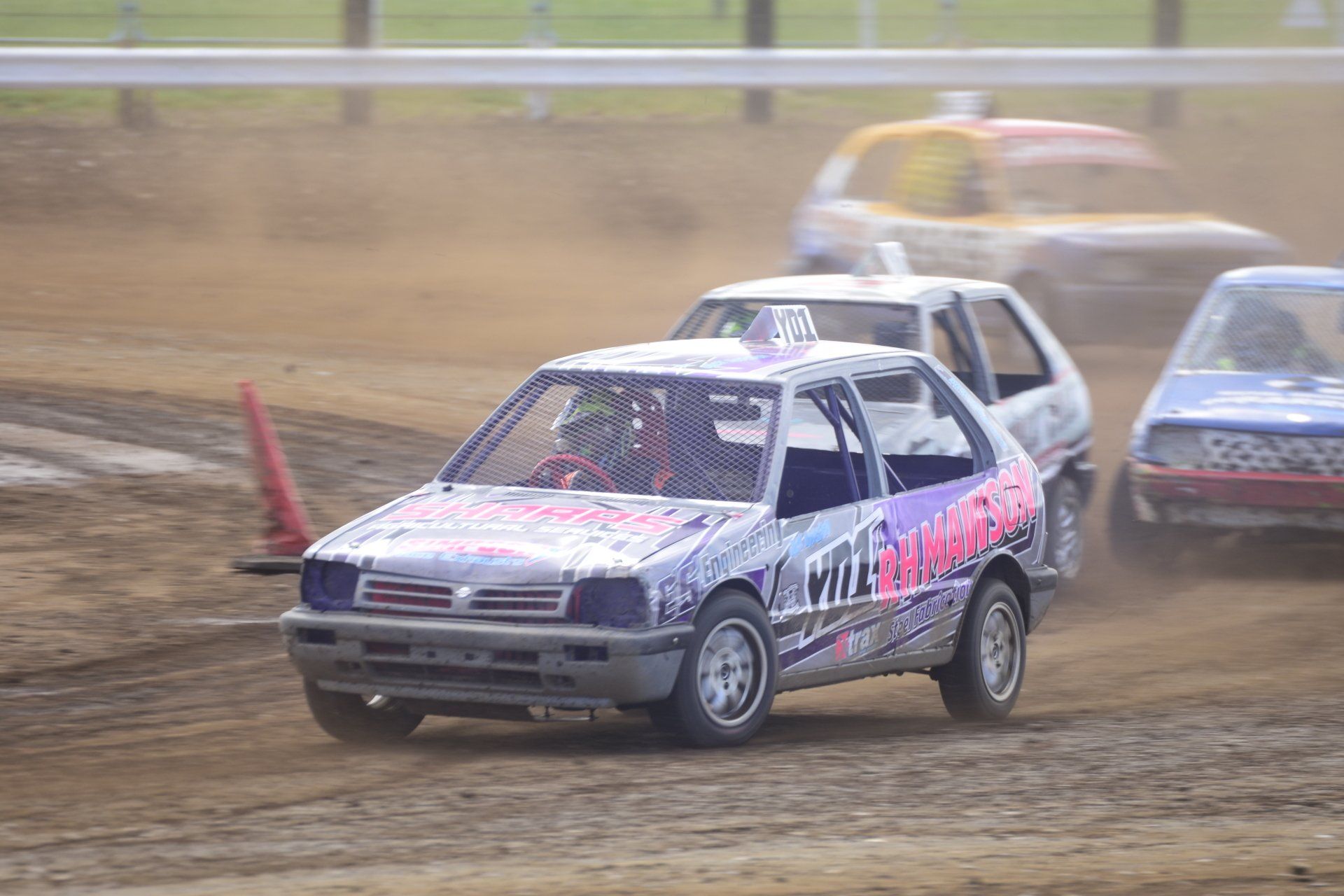 A group of cars are racing on a dirt track.