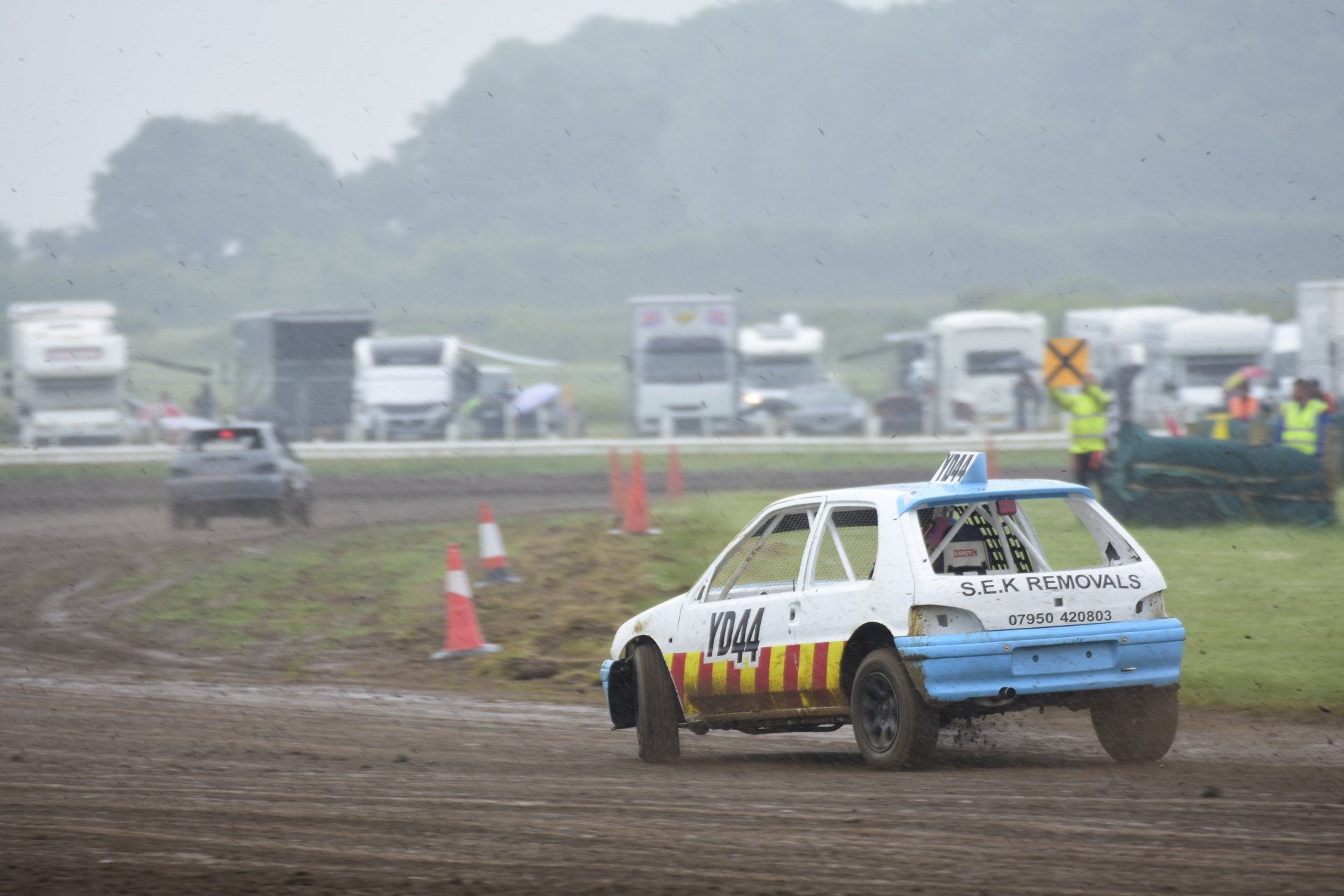 A blue and white race car is driving down a dirt road.