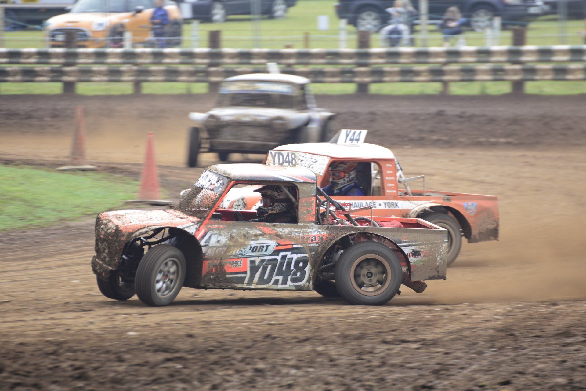 A group of cars are racing on a dirt track.