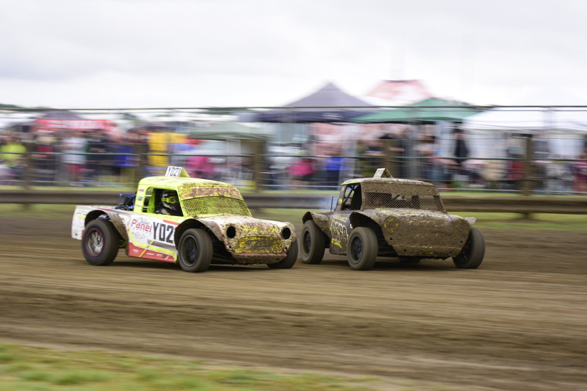 Two dirt cars are racing on a dirt track.