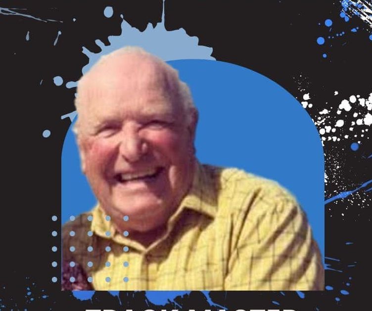 A man in a yellow shirt is smiling in front of a blue background