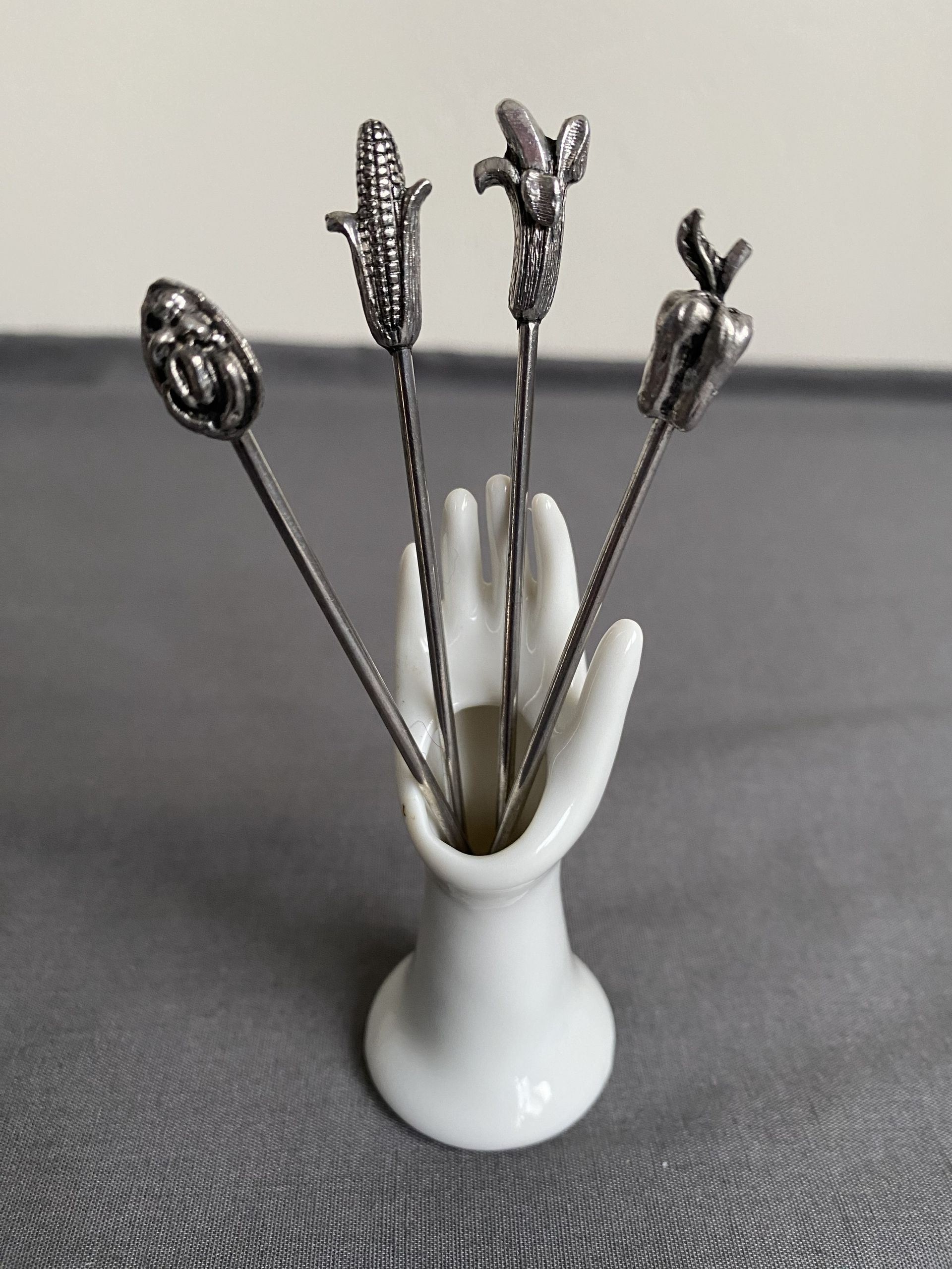 Houder hand met 4 verzilverde cocktailvorkjes