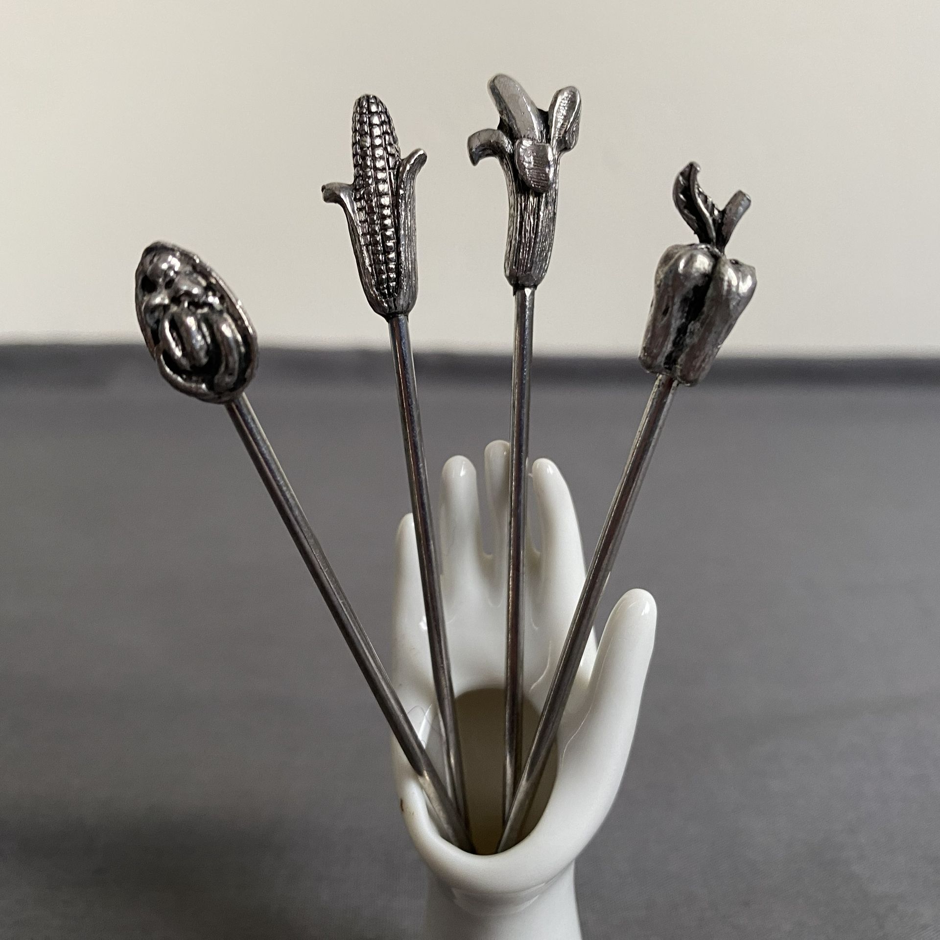 Houder hand met 4 verzilverde cocktailvorkjes