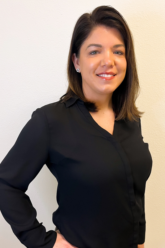 Smiling woman in a black blouse standing against a light background