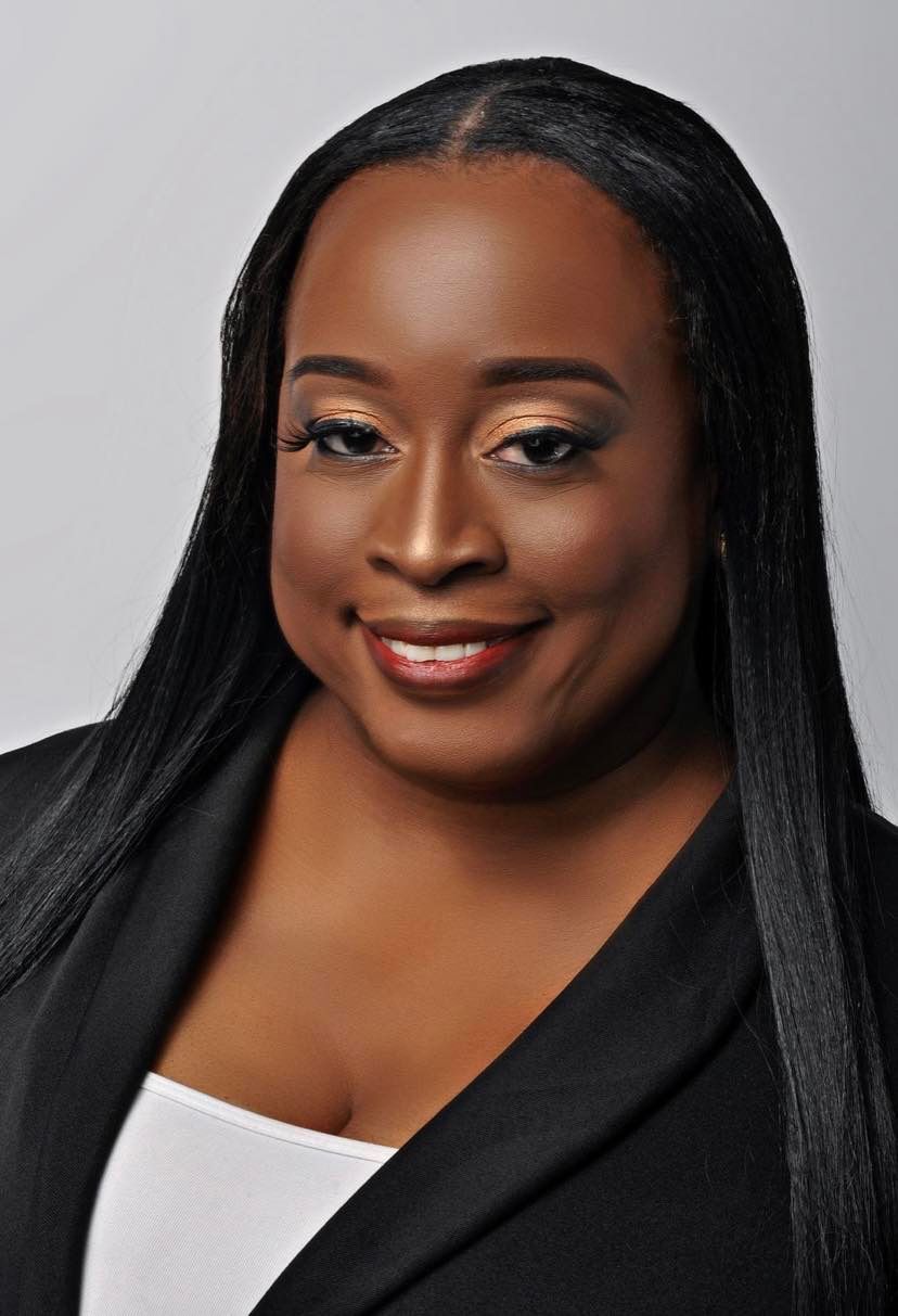 A woman with long black hair is wearing a black jacket and a white shirt.