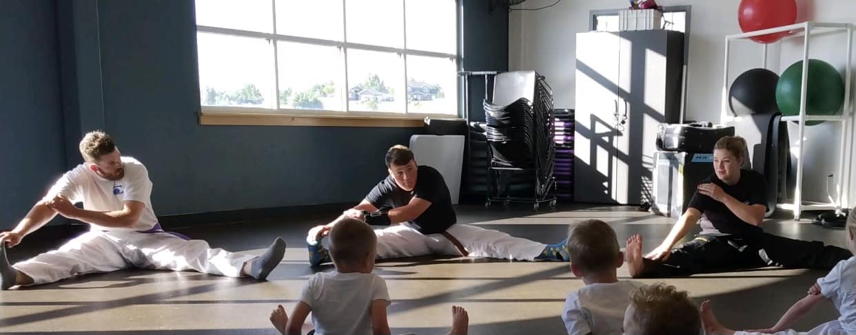 People stretching with children in a fitness room.
