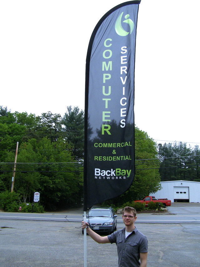 A man is holding a large flag that says computer services