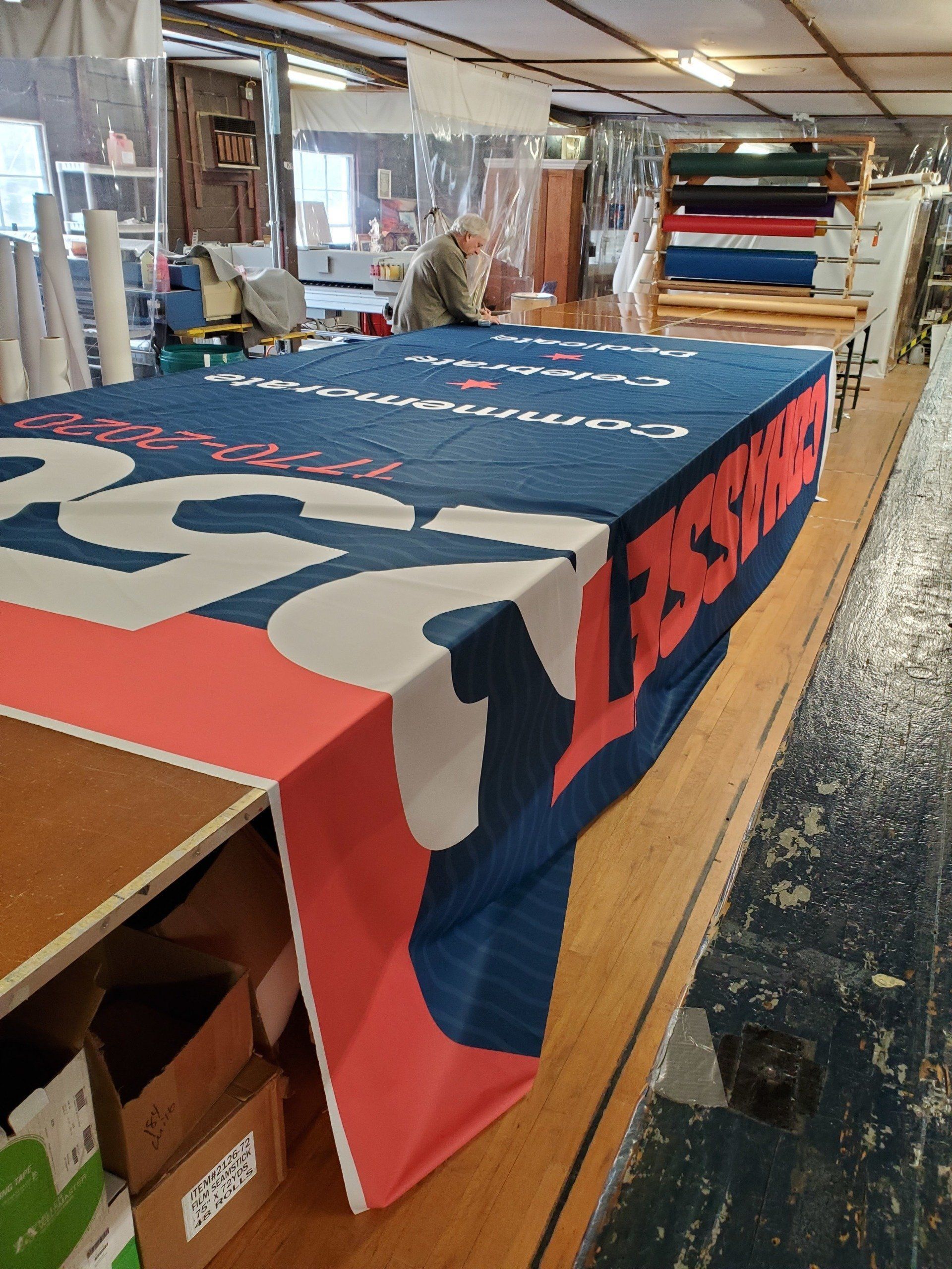 A man is working on a large piece of fabric in a factory