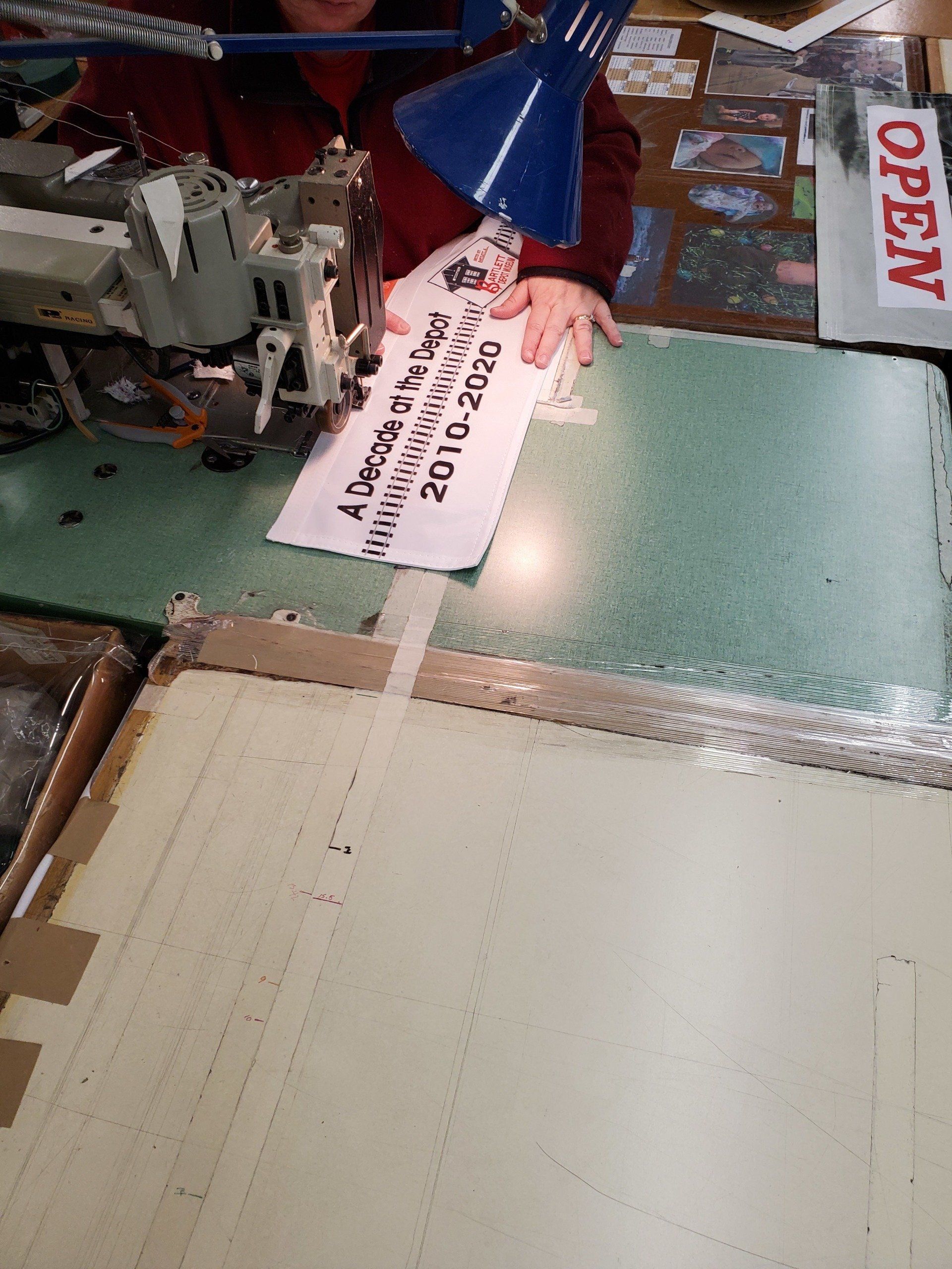 A person is sitting at a table using a sewing machine