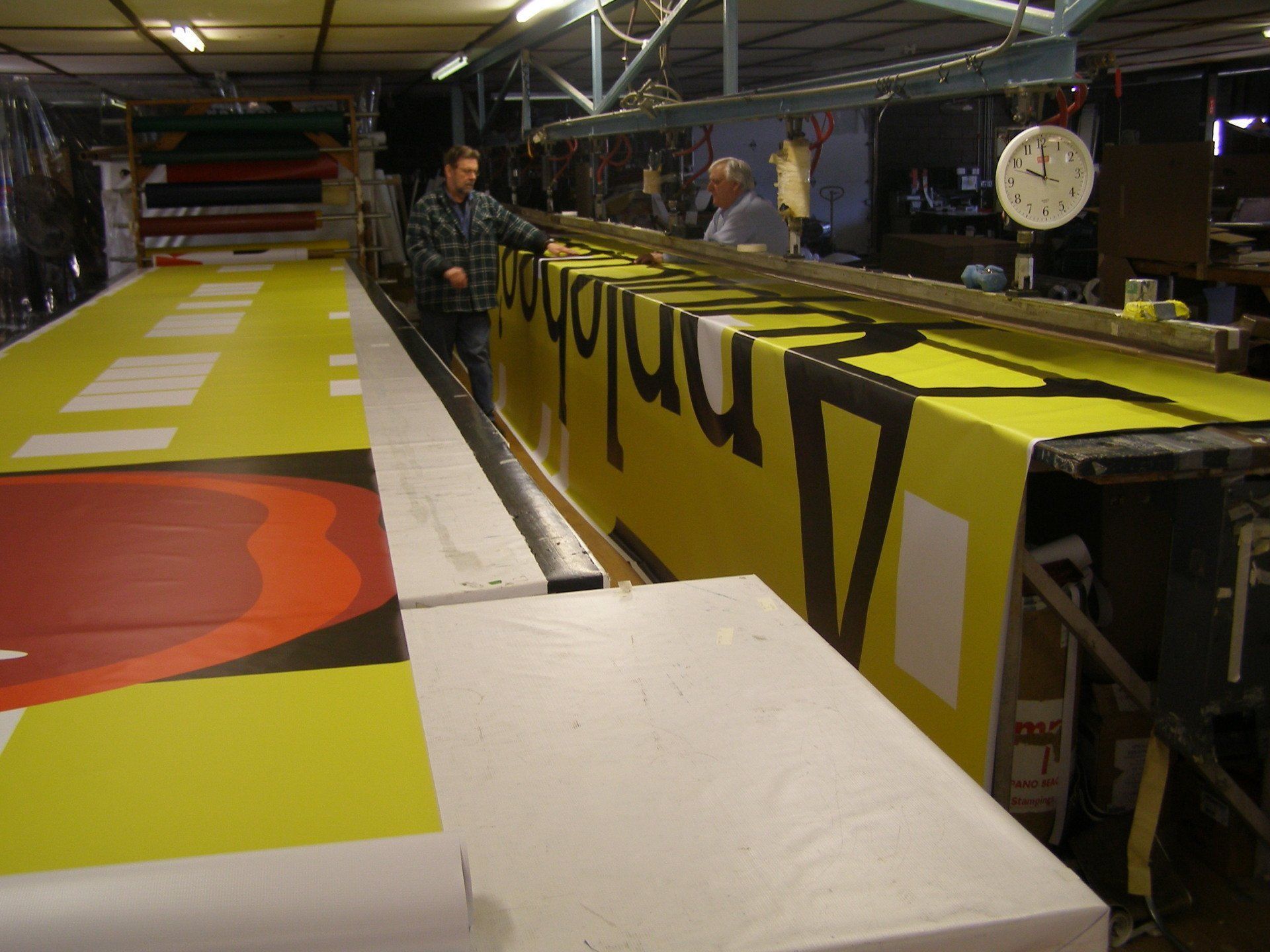 A man stands in front of a large yellow sign