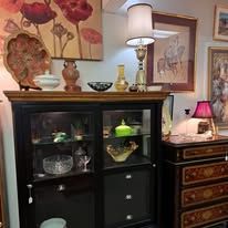 Antique cabinet with decorative items, framed art, and lamp.