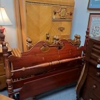 Wooden bed frame and tall wooden wardrobe in a room.
