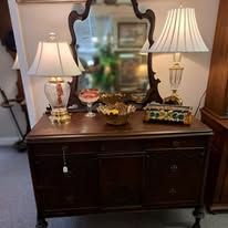 A dark wooden sideboard with a mirror and lamps, in a room.