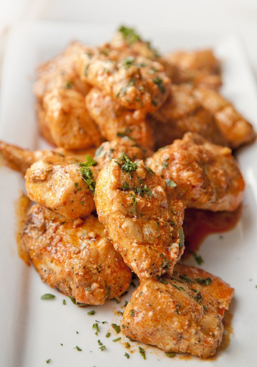 Chicken wings with creamy orange sauce on a white rectangular plate.