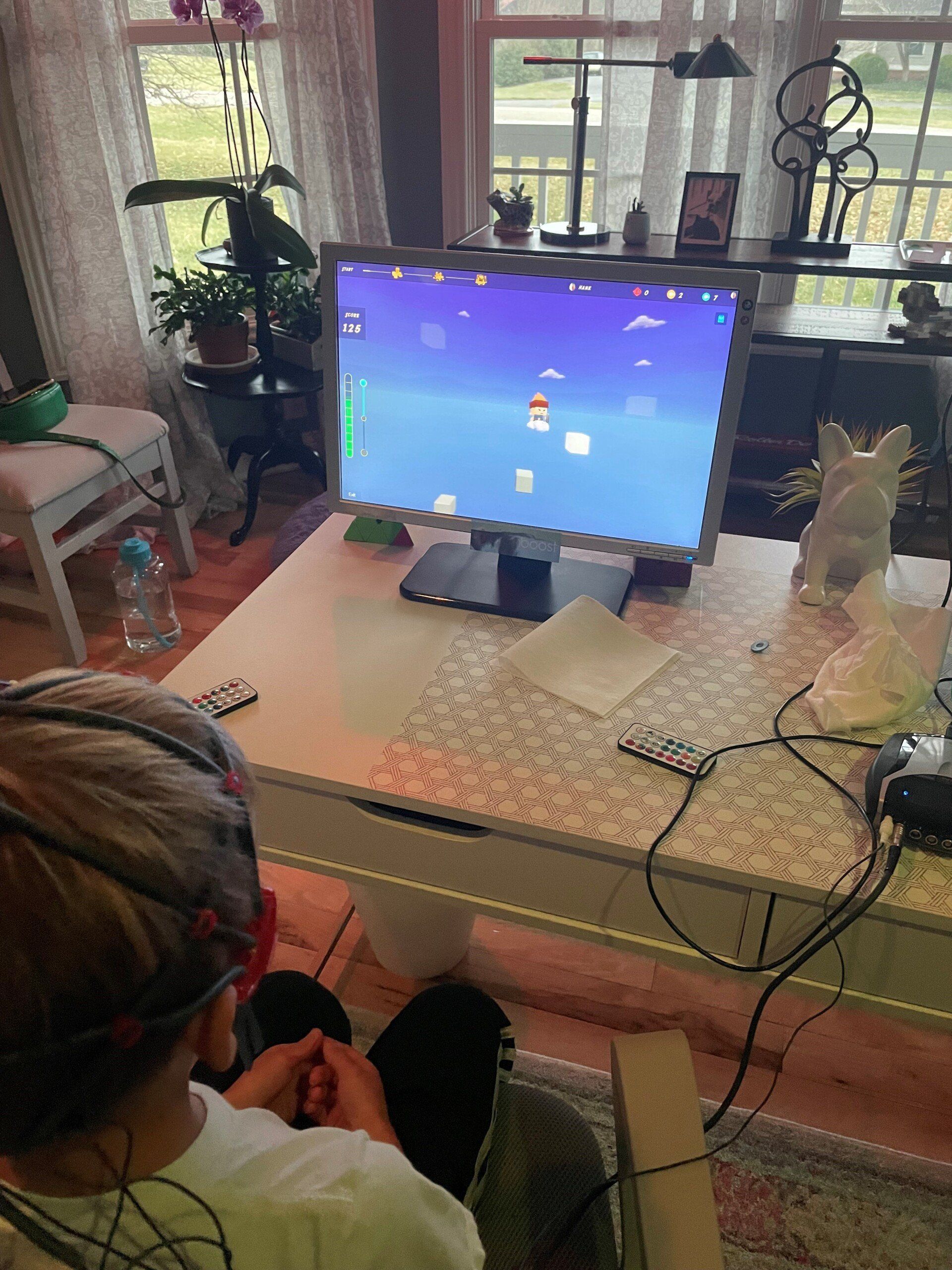 Person playing a video game on a computer. The player is wearing a headset with wires.