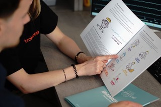 Two people looking at a brochure with illustrations and text, one person pointing.