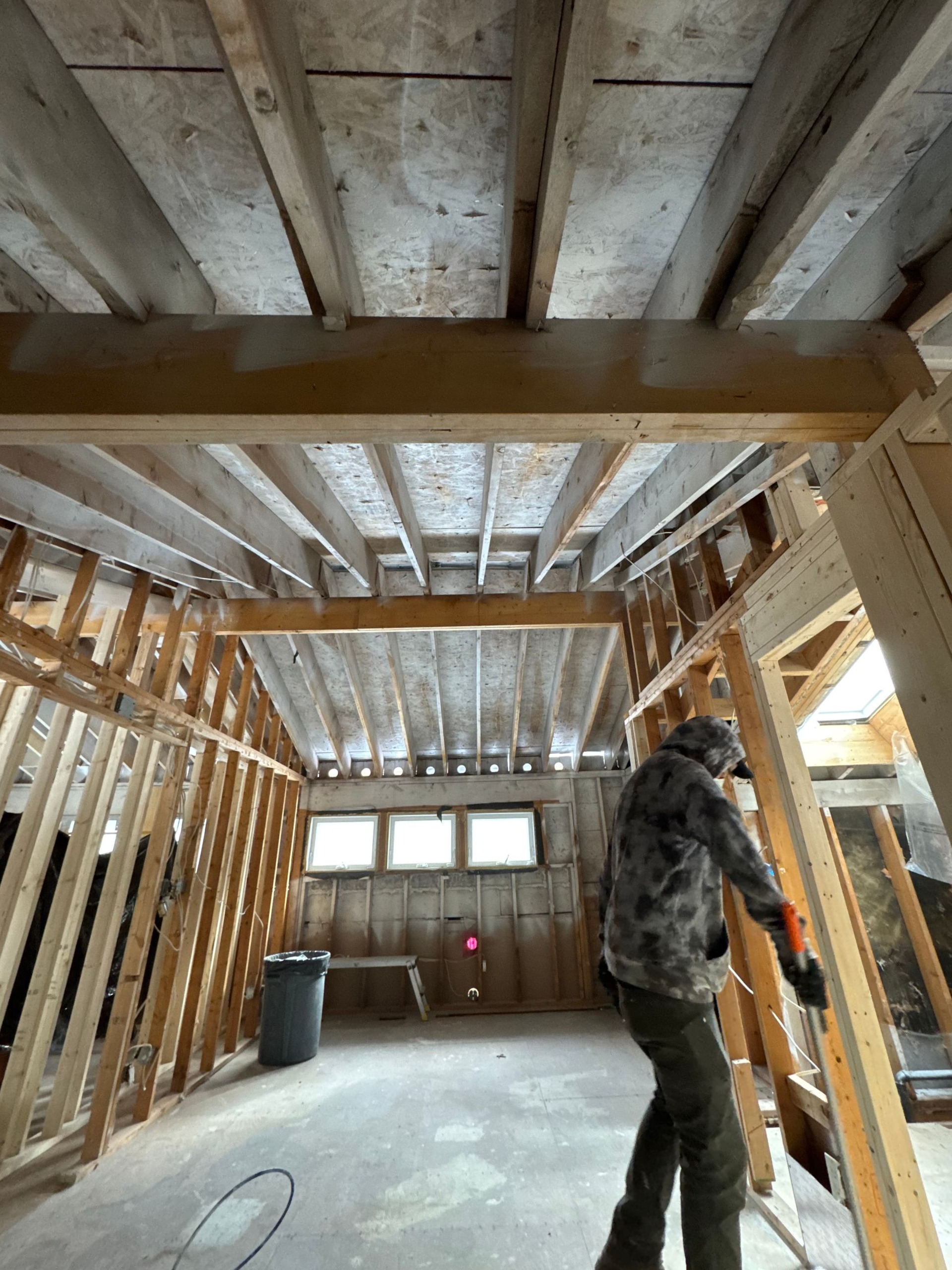 Interior renovation; person holding wood in a room with exposed beams and framing.