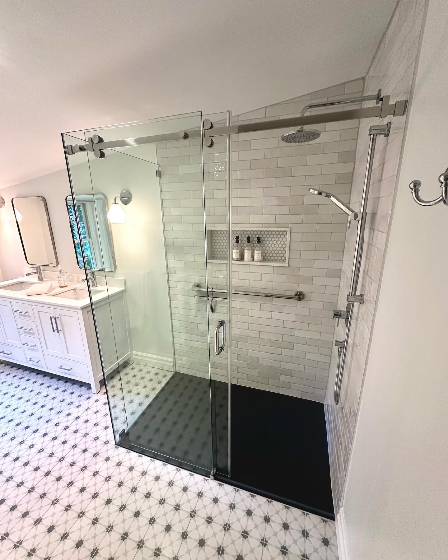 Modern bathroom with glass shower enclosure, white subway tile, black shower base, and handicap grab bars.