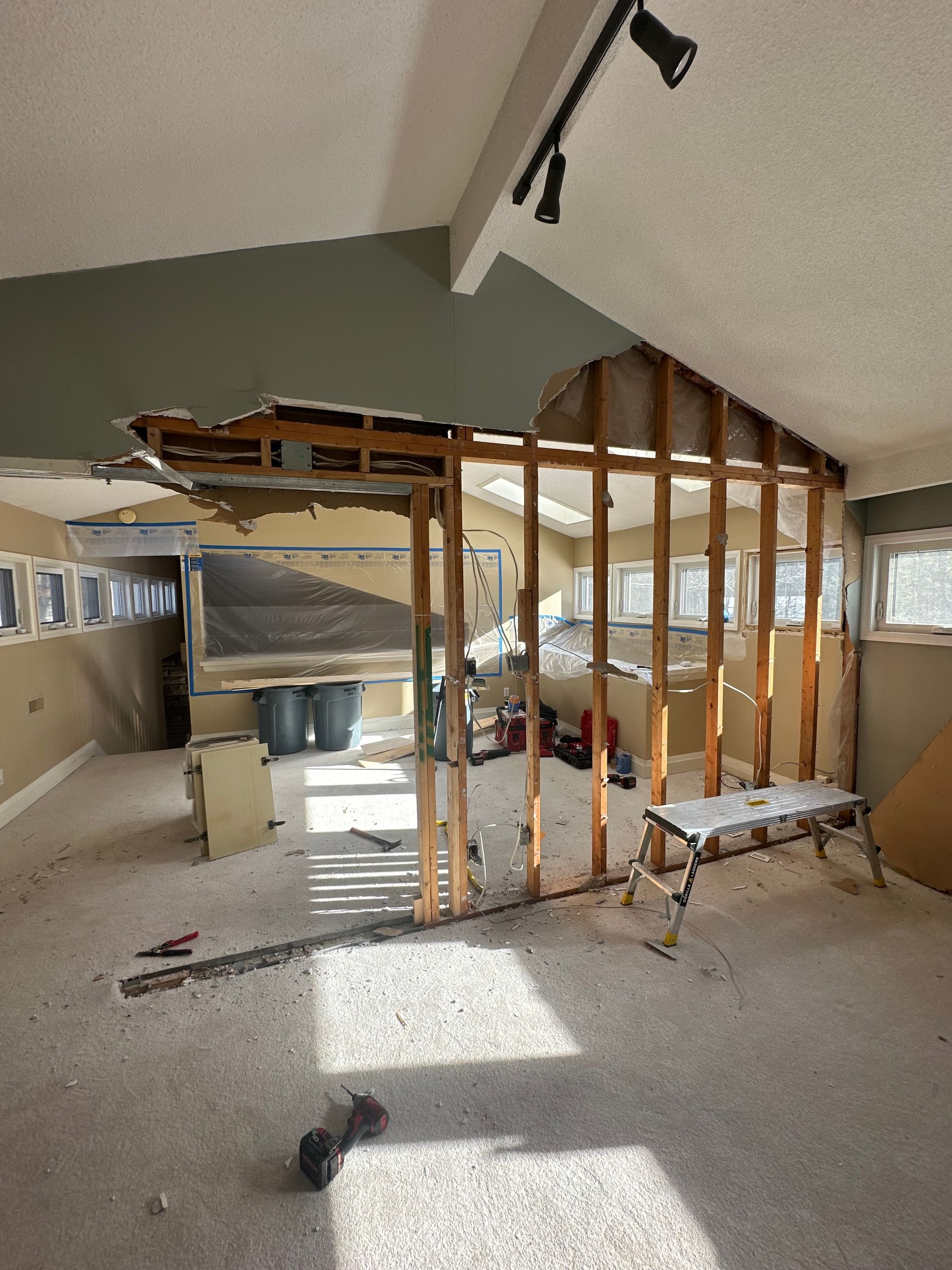 Room undergoing renovation, exposed wood framing and ceiling damage. Debris on floor.