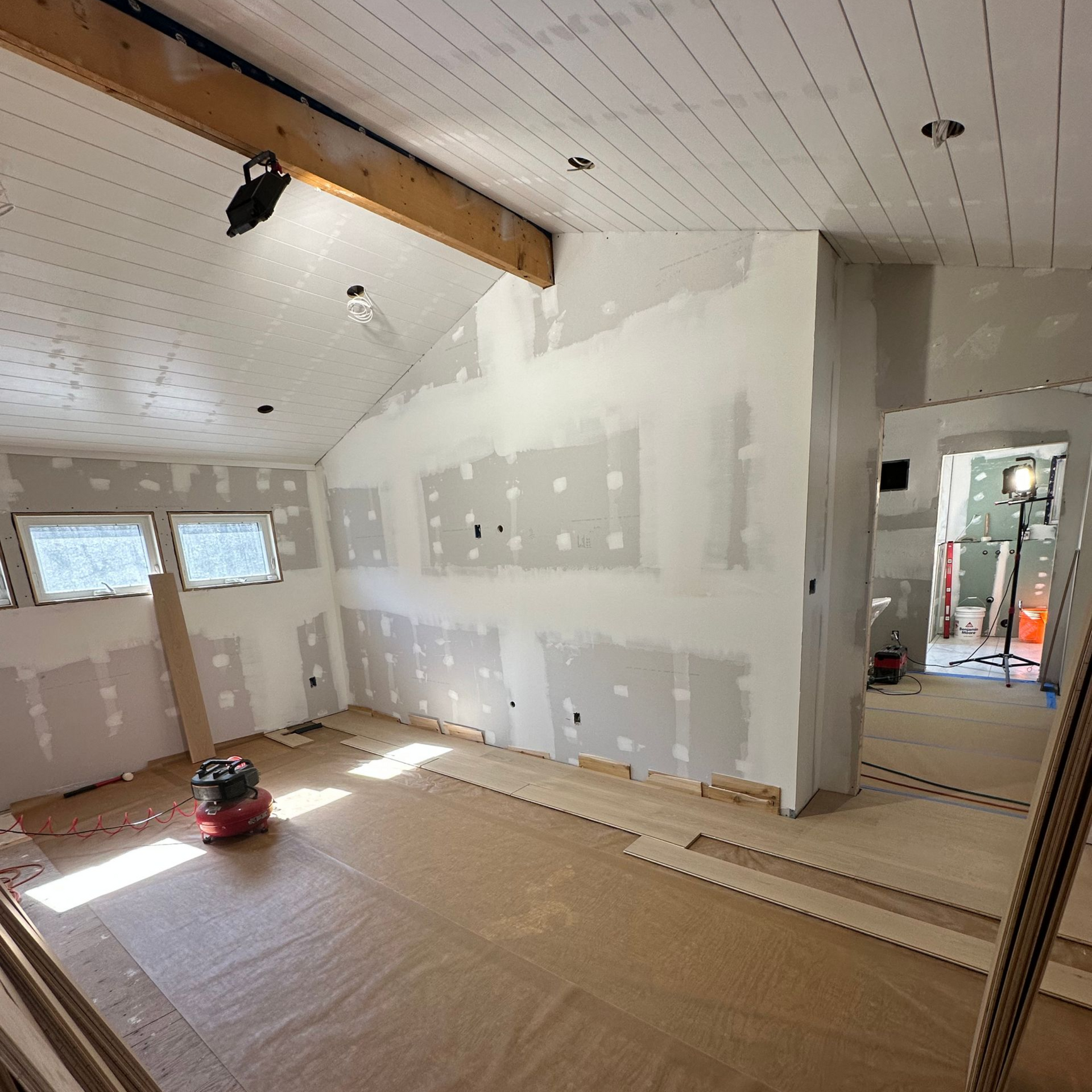 Room under construction with drywall and exposed wood, bright.