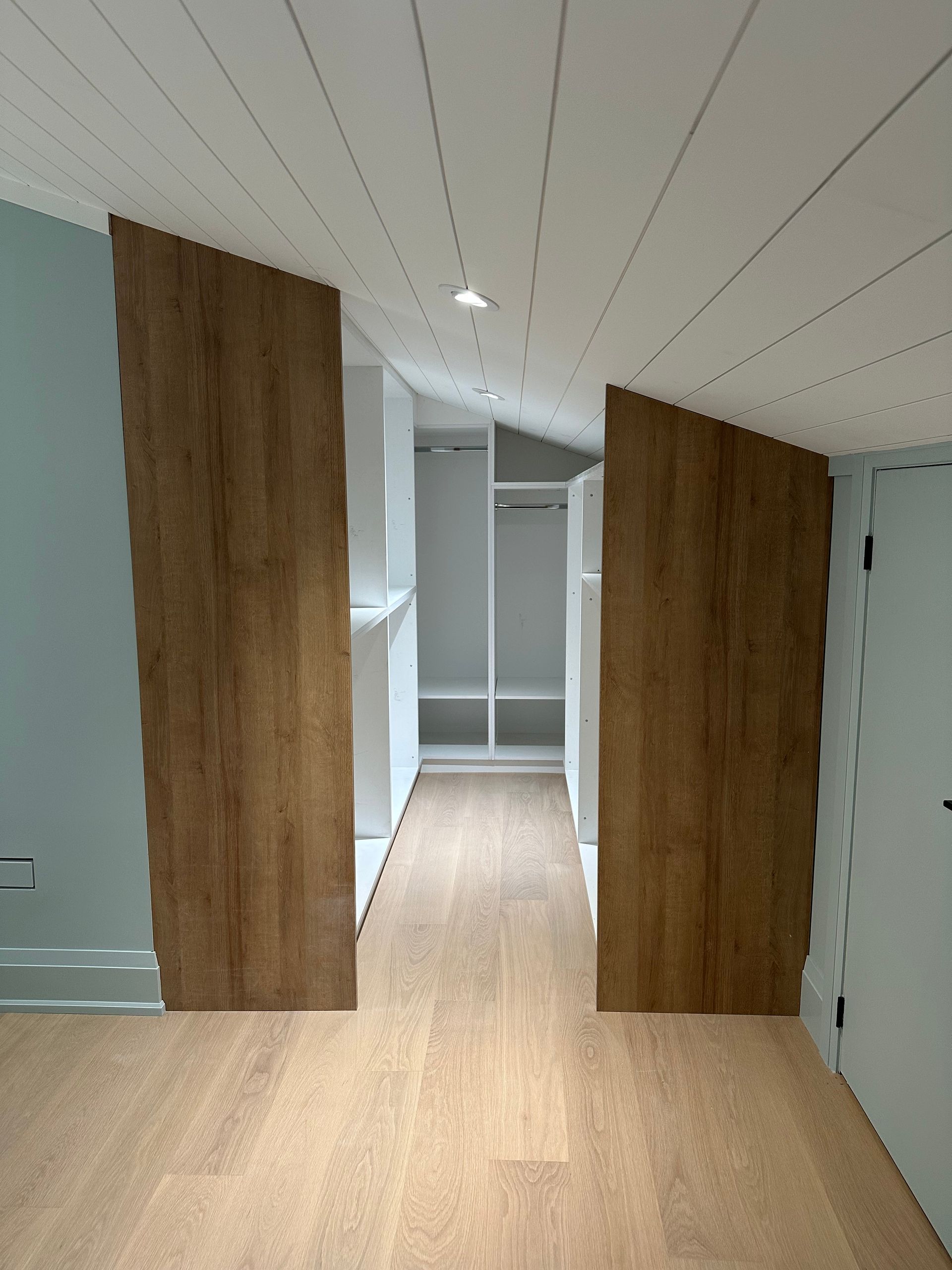 Bedroom with two angled wooden panels leading to a white closet.