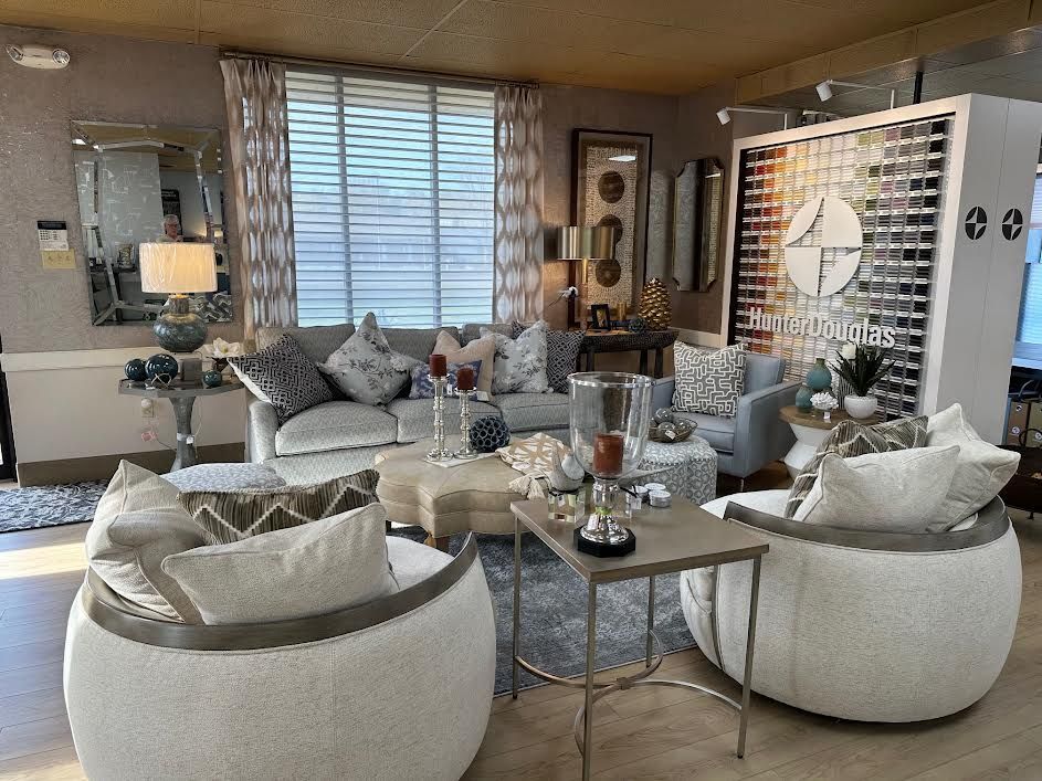 Living room furniture display with neutral colors, decorative pillows, mirrors, and lamps.