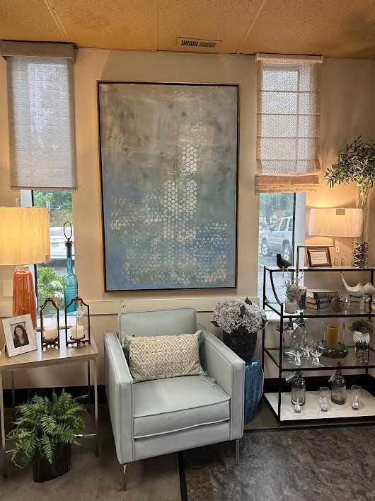 Living room setting with a light blue armchair, large artwork, and side tables.