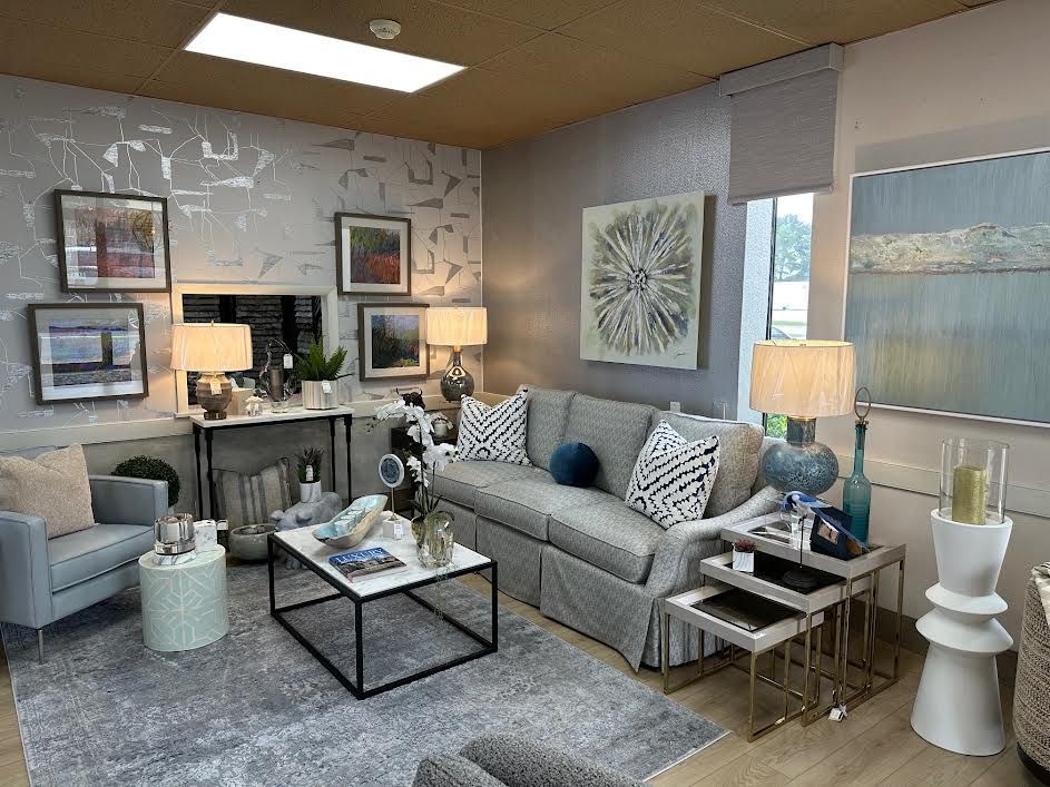 Living room with gray sofa, armchairs, coffee table, art, lamps, and a patterned rug.