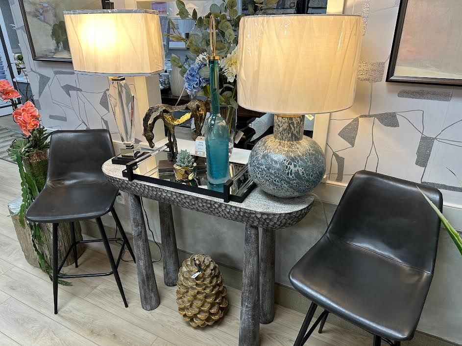 Two gray chairs flank a decorative table with lamps and decor.