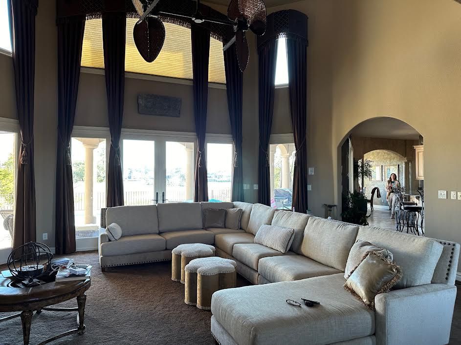 Spacious living room with sectional sofa, large windows, and dark blue curtains.